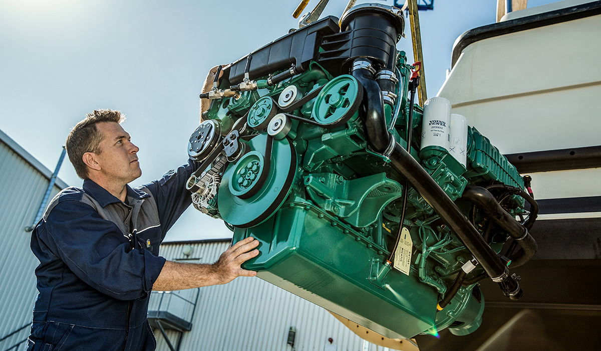 Photo of technician guiding Volvo Penta engine that is being lowered into a boat during a repower project.